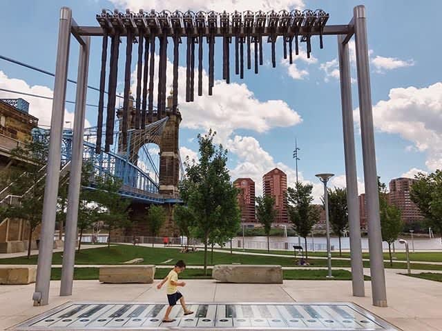 photo of a little boy in a yellow shirt walking across a foot paino at smale riverfront park in cincinnati oh
