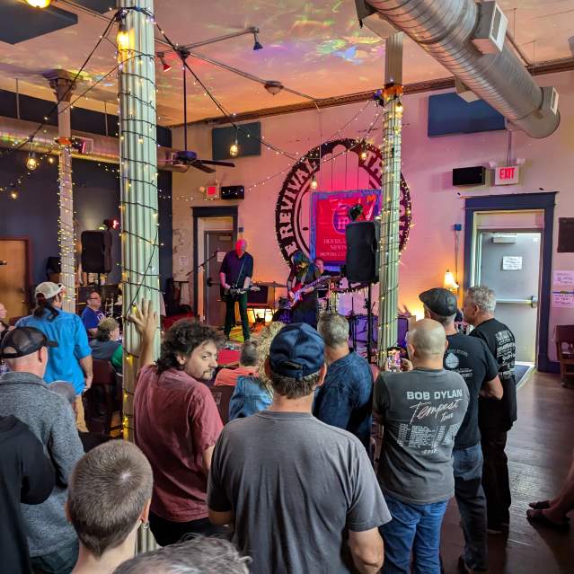 A group of people watch the stage where a group performs.