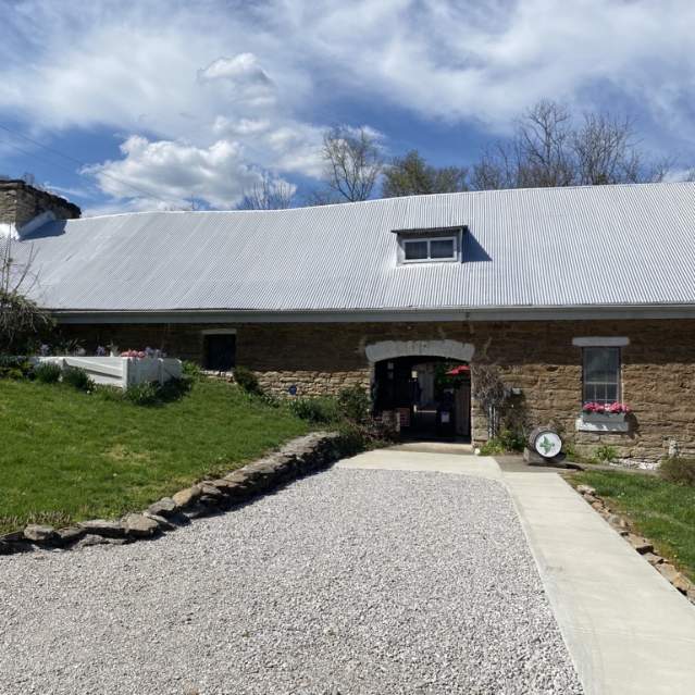 Image is the outside, front facade of the Baker Bird Winery with wooden barrel out front that say's "Baker Bird".