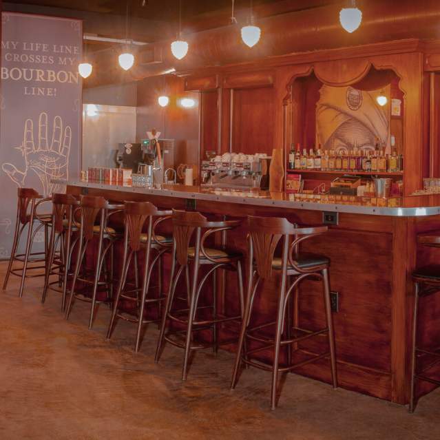 A warm toned bar with several stools pulled in around. On the left the logo for Second Sights fills the wall with a 3-D, fuzzy, mustache.