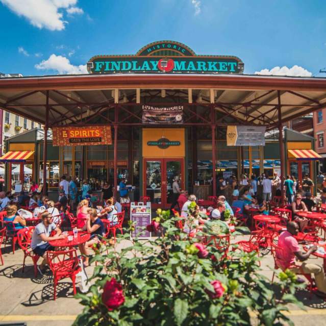Exterior of Findlay Market showing the sign. Many bistro tables fill the patio for people to sit and eat.