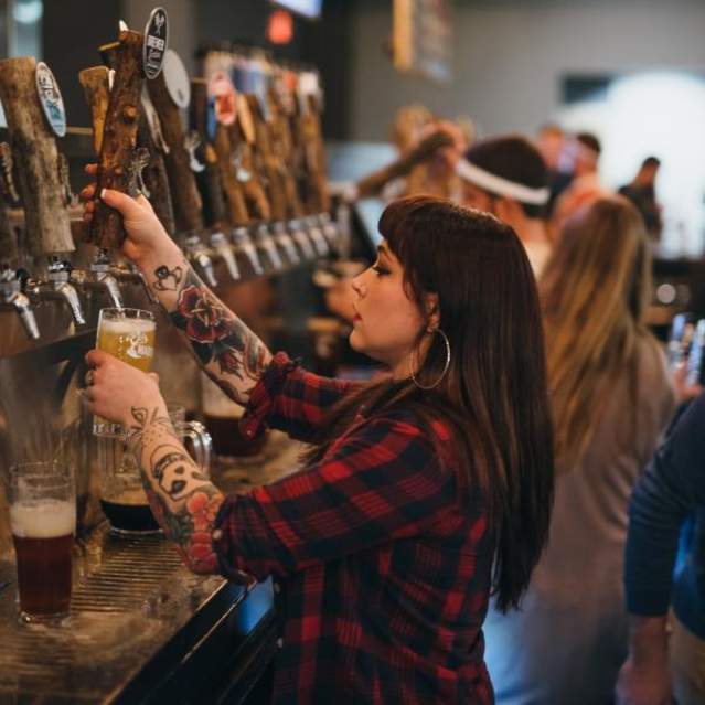 female bartender pouring beer into a glass at Mad Tree bar
