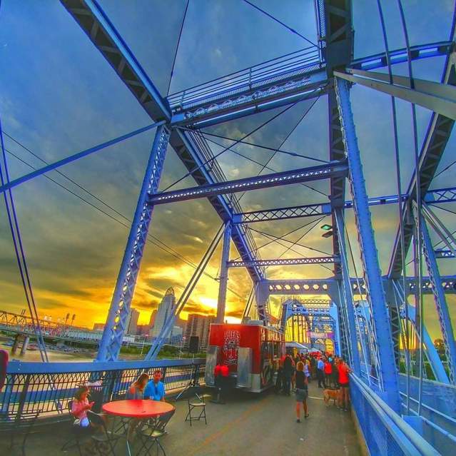 Tables and food vendors set up on the Purple People Bridge at sunset.