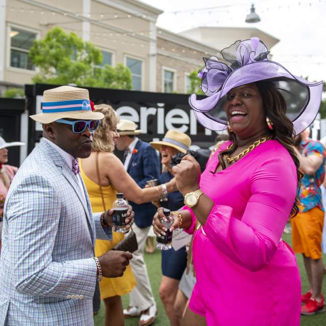 Image is of a male and female dressed up in Derby attire on the Levee.