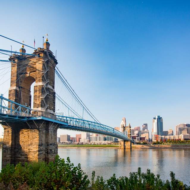 The Roebling Suspension bridge leading to downtown Cincinnati's skyline under a sunny blue sky