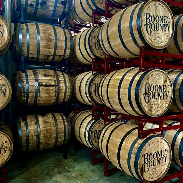 Bourbon barrels stamped with Boone County and stacked on red shelves