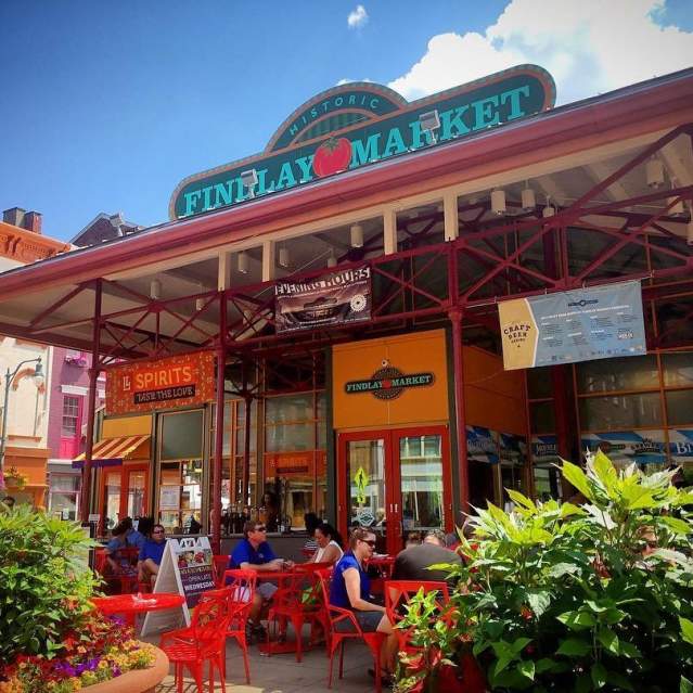 The entrance of Findlay Market during the day with couples sitting at tables surrounded by flowers.