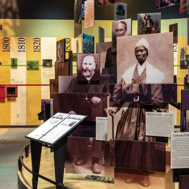 A museum exhibit showcasing people made up of modular photos. A timeline runs in the background.