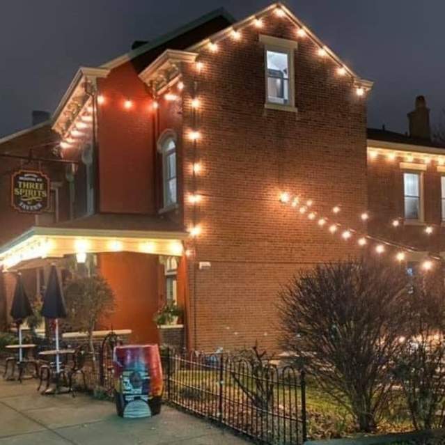 A red brick building at night with glowing lights around the exterior and over a courtyard.