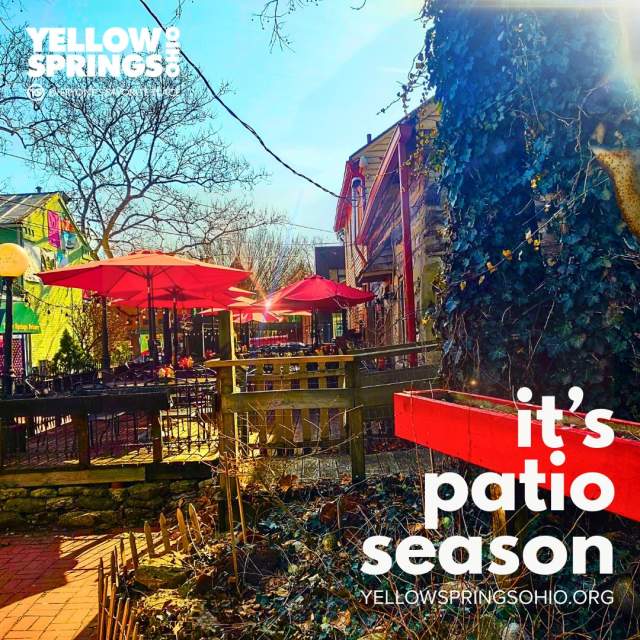 A patio with colorful umbrellas. Text reads Yellow Springs Ohio and It's Patio Season.