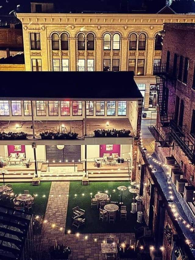 Looking down on an illuminated patio with brick walls and the turrets of Mother of God church in the background