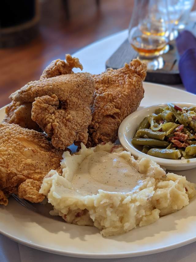 A white plate with fried chicken, green beans and mashed potatoes at Purple Poulet