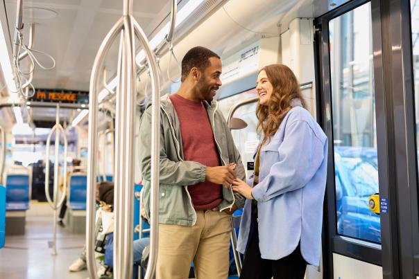 A couple laughs and holds hand on the streetcar