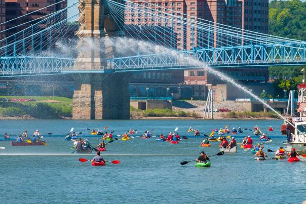 A large group of kayaks paddle under the Roebling Suspension Bridge in Covington, Kentucky during Paddlefest.