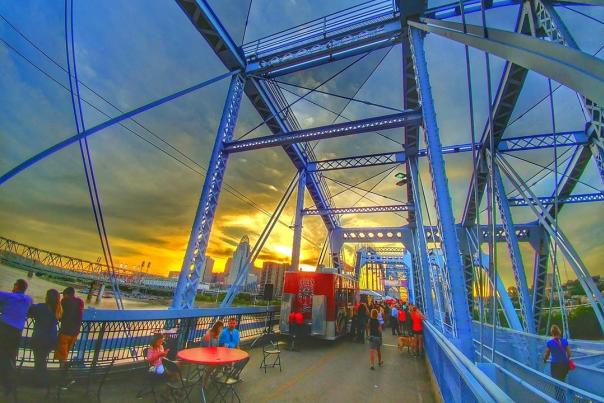 Tables and food vendors set up on the Purple People Bridge at sunset.