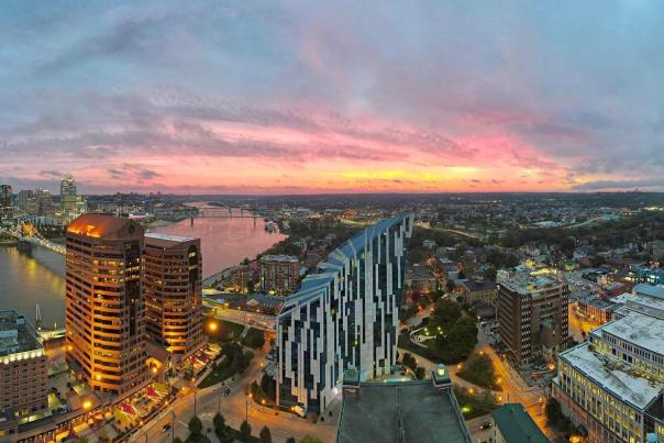 The sky glowing pink and gold with a sunrise behind the skyline of Covington, Ky. with Cincinnati, Ohio in the background