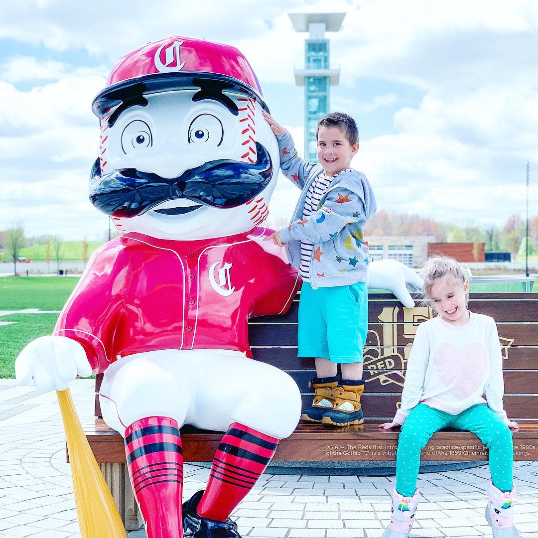 photo of the cincinnati reds mascot with two kids sitting on bench for 150th anniversary of major league baseball celebration in cincinnati oh