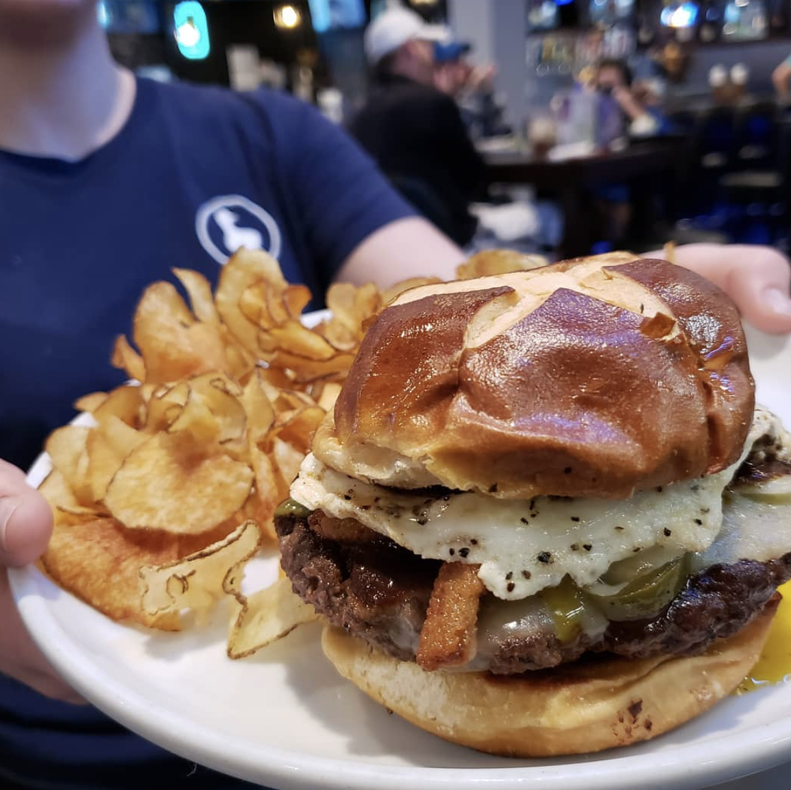 burger on a plate surrounded with saratoga chips at lucky duck pub in burlington ky
