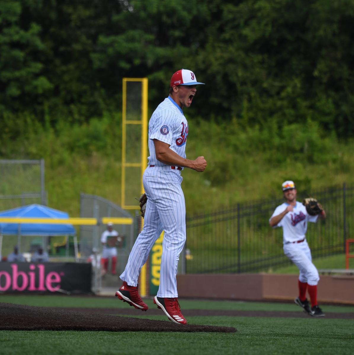Image is of a pitcher jumping up with a big smile on his face.