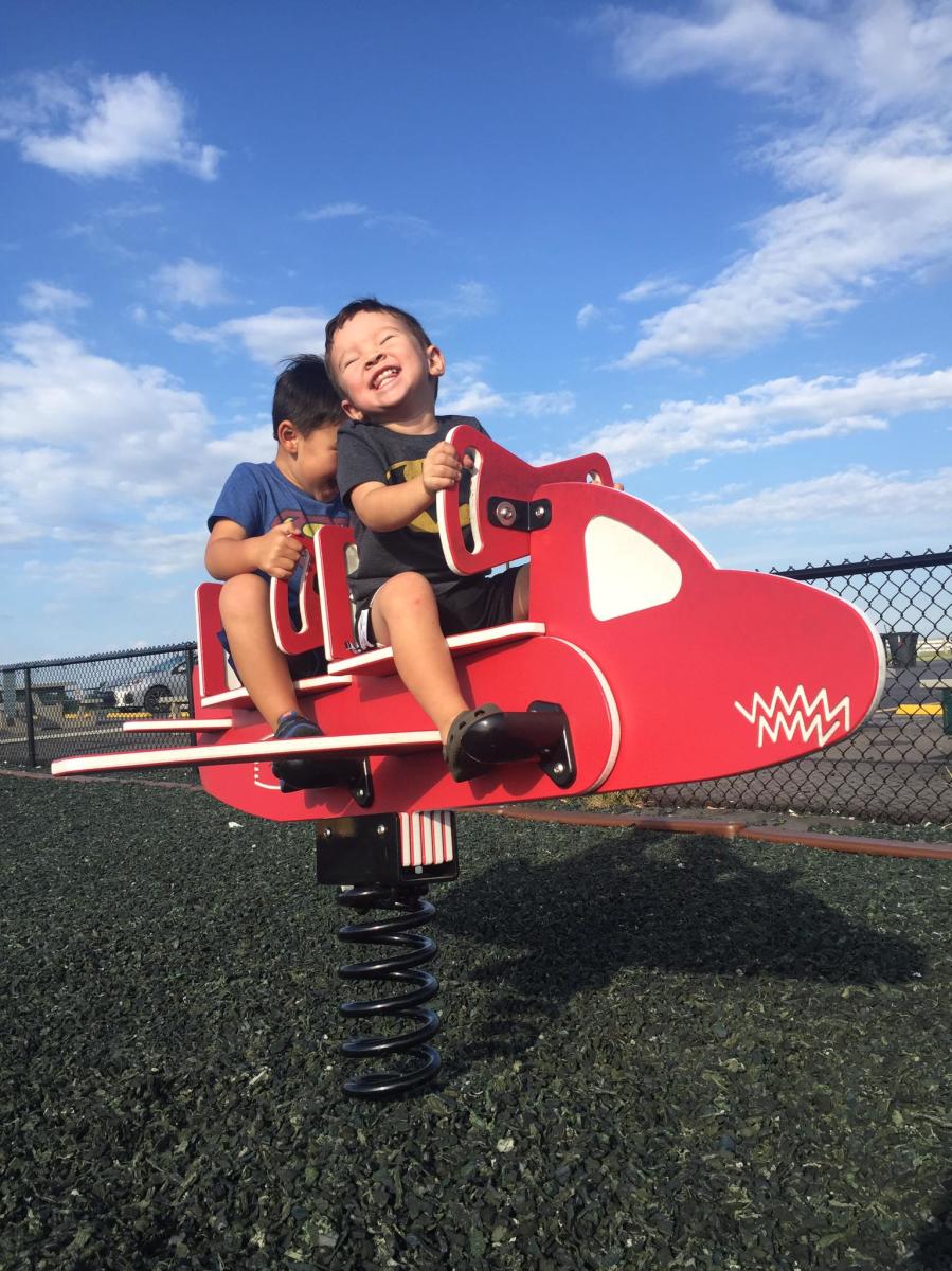 smiling boy on red airplane playground equipment at CVG airplane viewing area in hebron kentucky near cincinnati