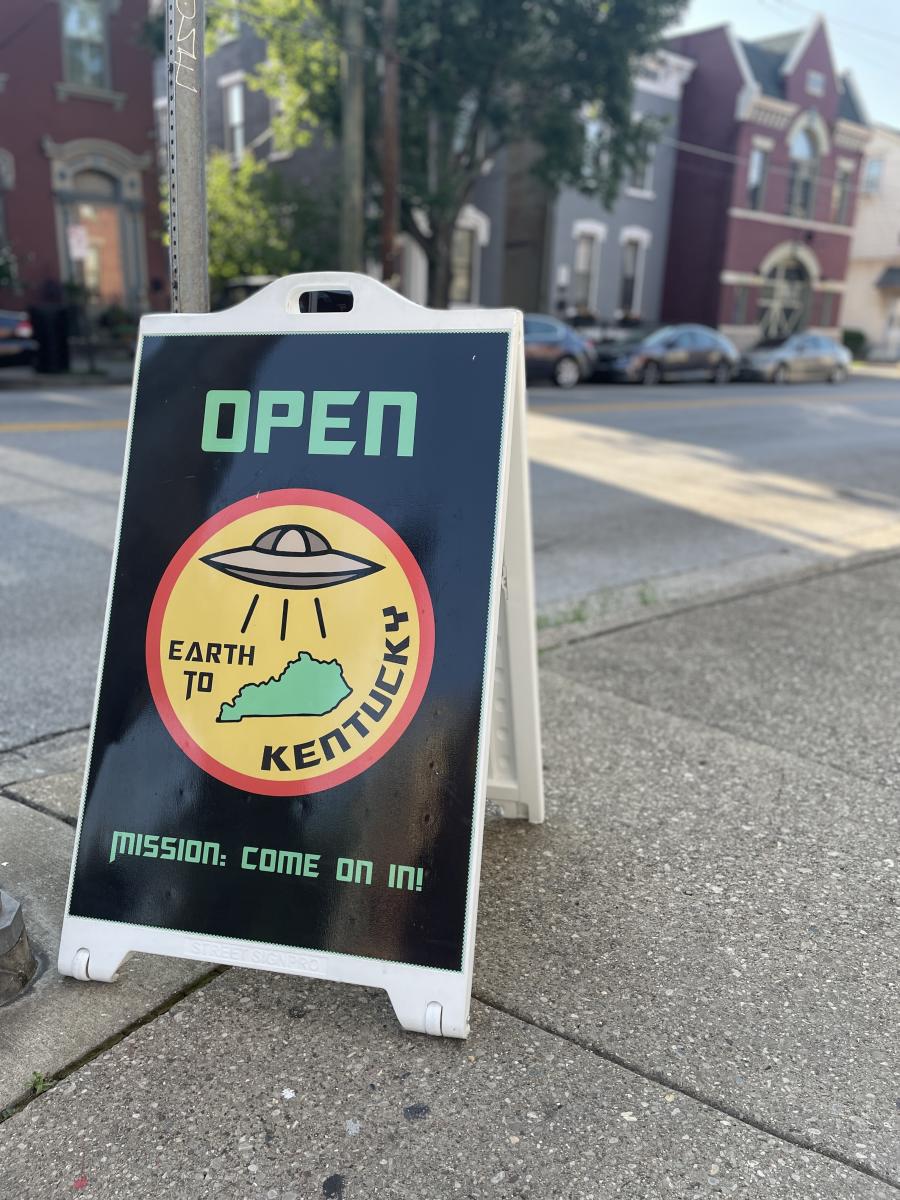 Outdoor street sign that say's "Open, Earth to Kentucky".