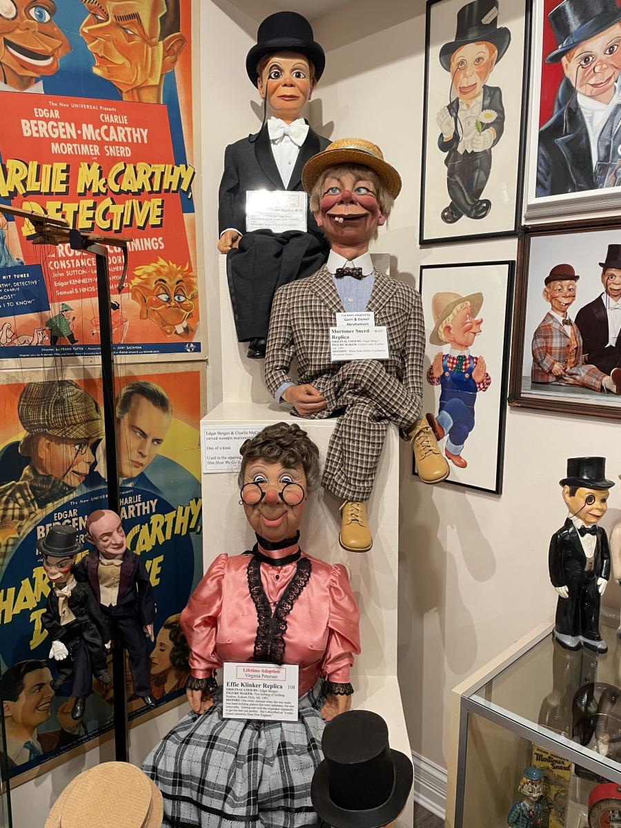 Image is of 3 dummies sitting one on top of the other, surrounded by posters.