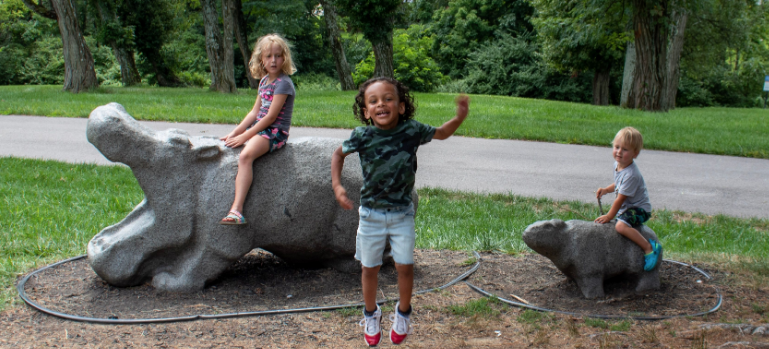 three children enjoying playing on concrete hippos at Florence nature park in Florence ky