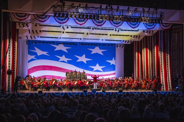 The Cincinnati Symphony Orchestra performs onstage with American flag decor as a backdrop