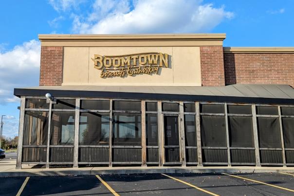 Image is of the side of Boomtown biscuits & whiskey building with their name above and the outdoor, covered patio below.
