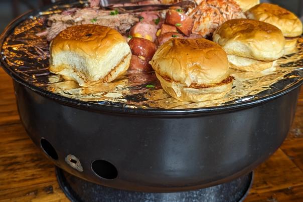 Image is of Shiners Grill Out which is a small grill with buns and different types of meat on top of it.