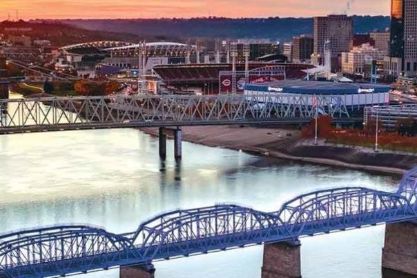 Image is an arial view of the Purple People Bridge spanning the Ohio River, connecting Newport, KY to Cincinnati, OH.