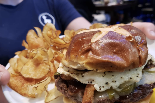 burger on a plate surrounded with saratoga chips at lucky duck pub in burlington ky