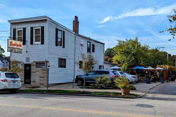 White clapboard two story building with an umbrella shaded patio on the side
