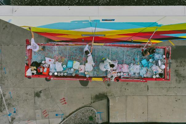 An aerial view of a crew painting a mural on the side of a building
