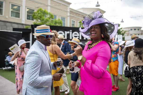 Image is of a male and female dressed up in Derby attire on the Levee.