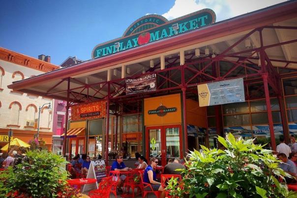 The entrance of Findlay Market during the day with couples sitting at tables surrounded by flowers.
