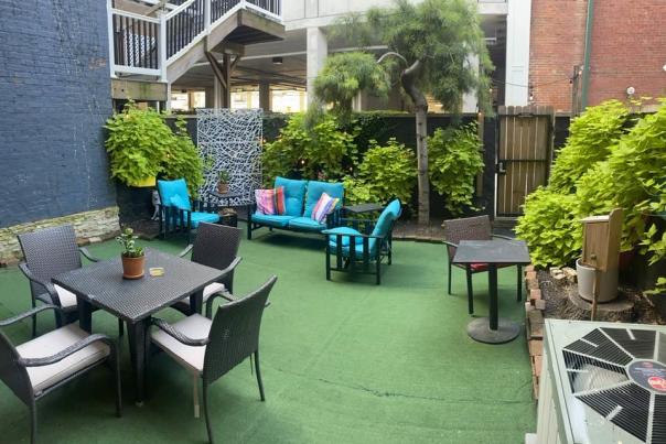 A private patio with several seating options. Green plants grow lush along the wall.