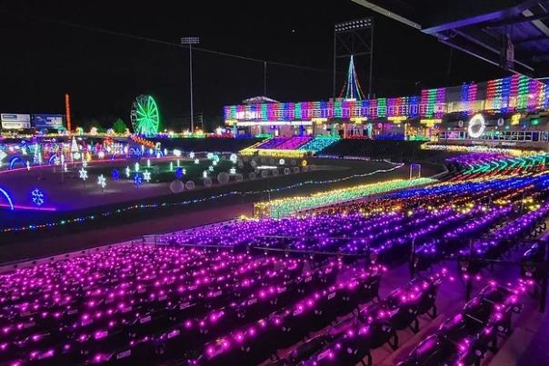 Nighttime display of holiday lights in pink, purple, green and yellow on the bleachers of the stadium.