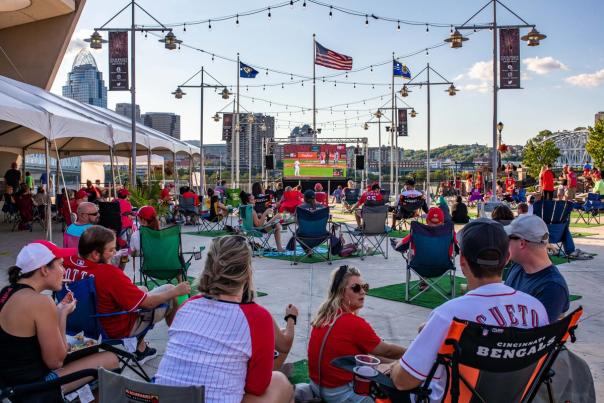 People sitting in lawn chairs wearing Red's gear watching the Red's play on an outside projection screen.
