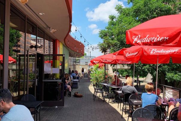 red umbrellas and black outdoor patio tables on a brick sidewalk in front of the gruff in covington ky