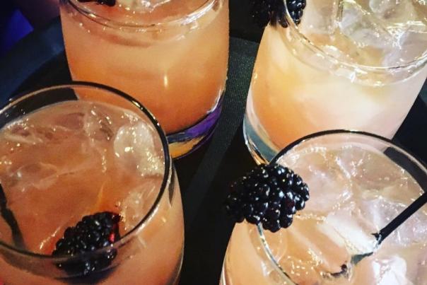 four bourbon glasses holding fruity bourbon cocktails and blackberries at the purple poulet bourbon bistro