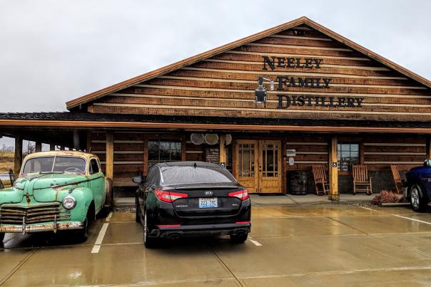 The exterior of Neeley Family Distillery, a wood building on the B-Line Bourbon trail in NKY, with an old bootlegger's car parked out front.