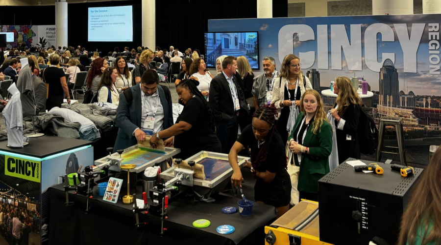A group of people in the booth screen printing t-shirts.