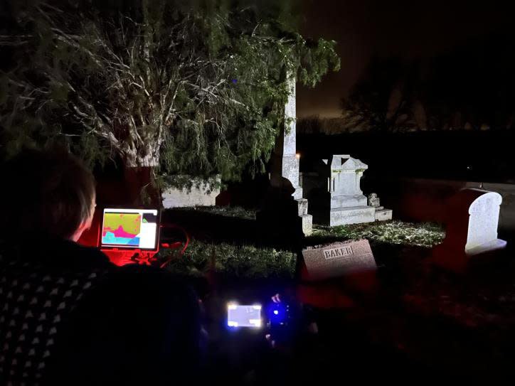 A person is observing a cemetery through an electronic device.