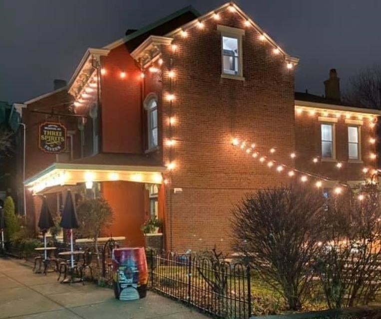 A red brick building at night with glowing lights around the exterior and over a courtyard.