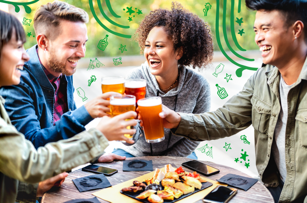 A group of people sit around a table, toasting beer glasses.