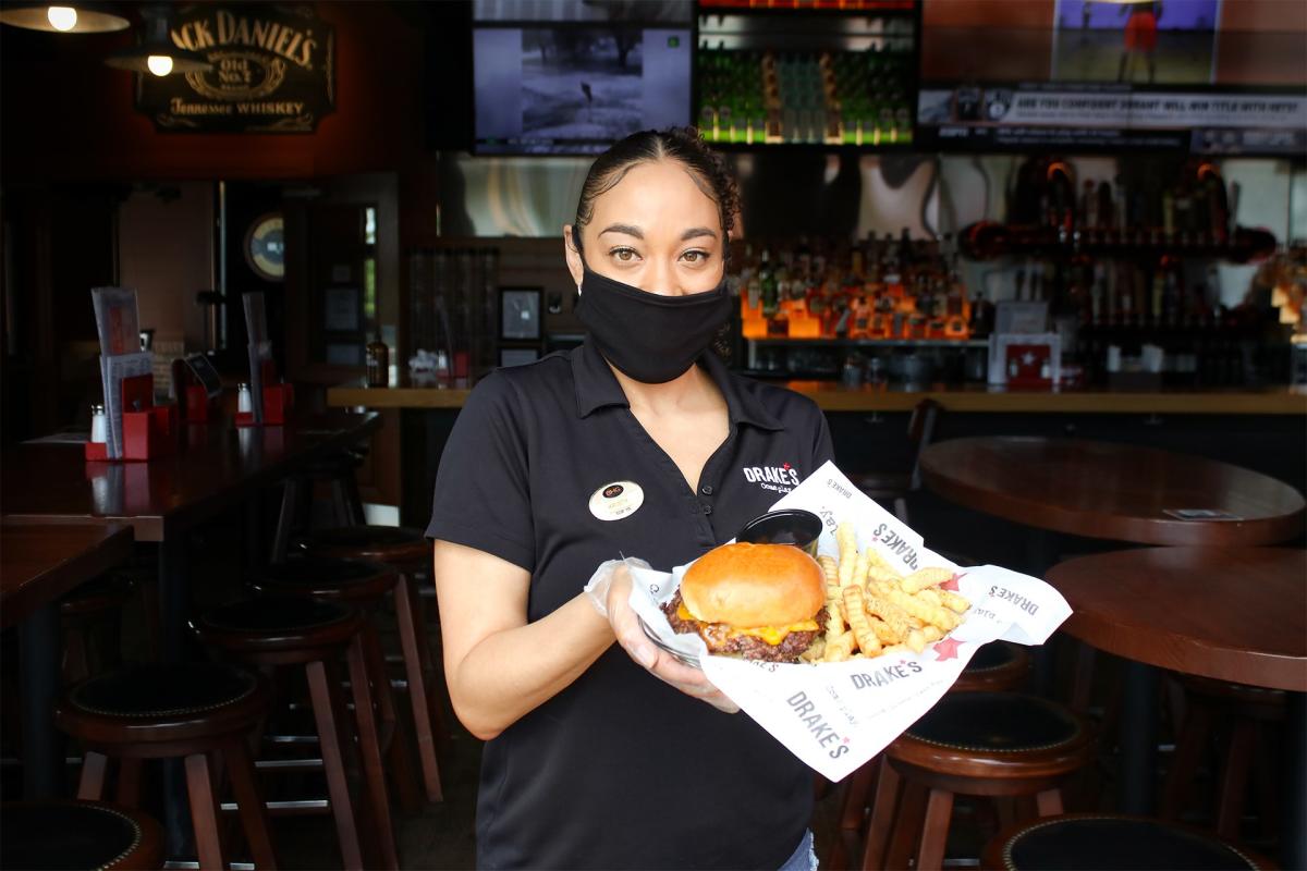 female server wearing a facemask and holidng a burger and fries at drake's florence, ky.