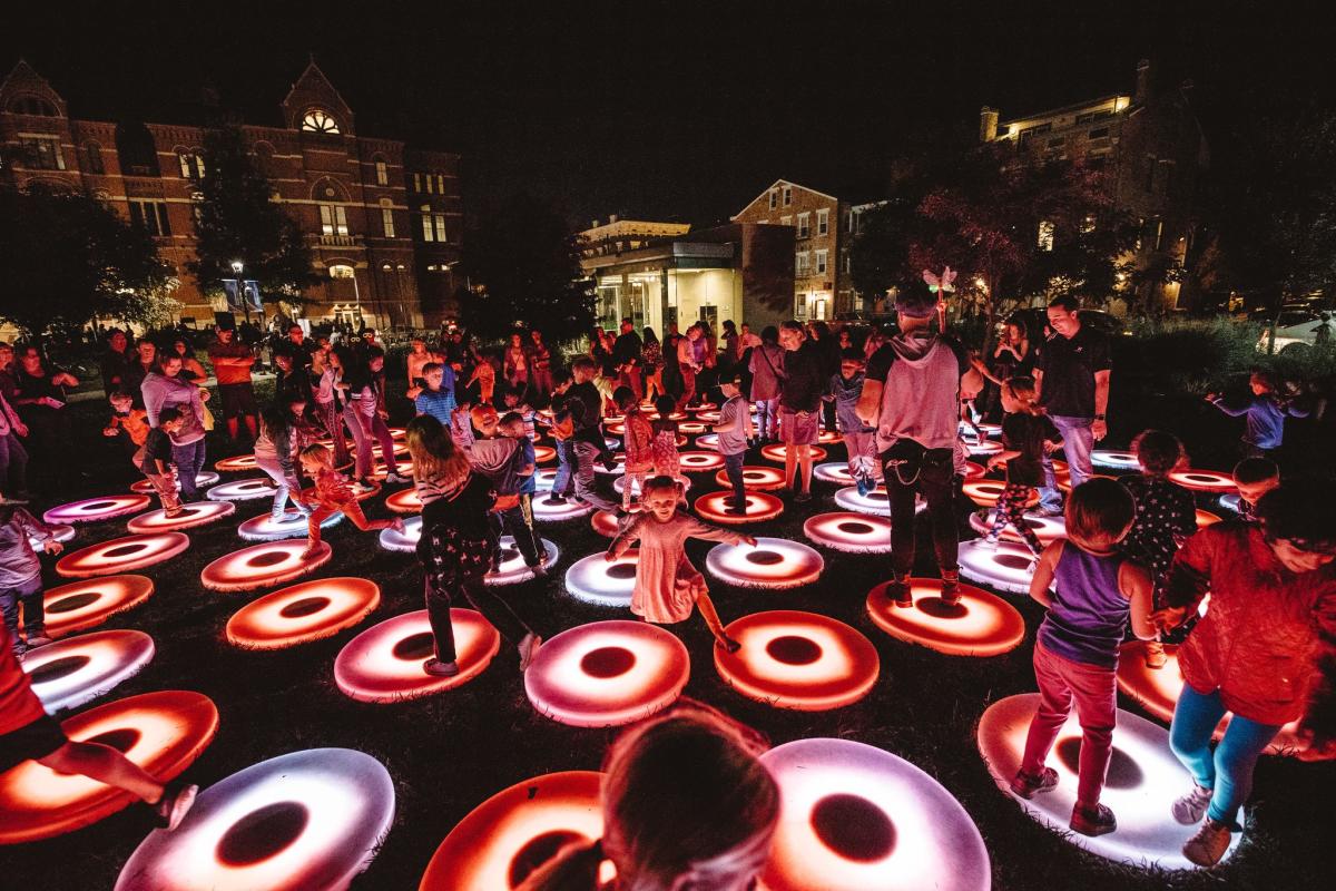 A crowd of people dancing on lighted up circles at BLINK Cincy
