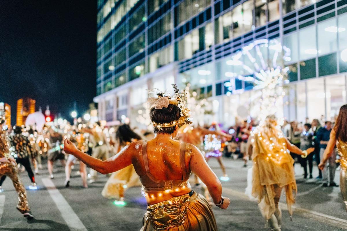 Danders dressed in gold with yellow lights in the BLINK Cincy parade