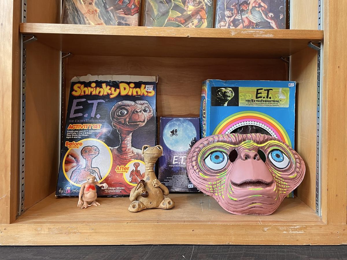 Image is a bookshelf with rare and vintage E.T. figurines.